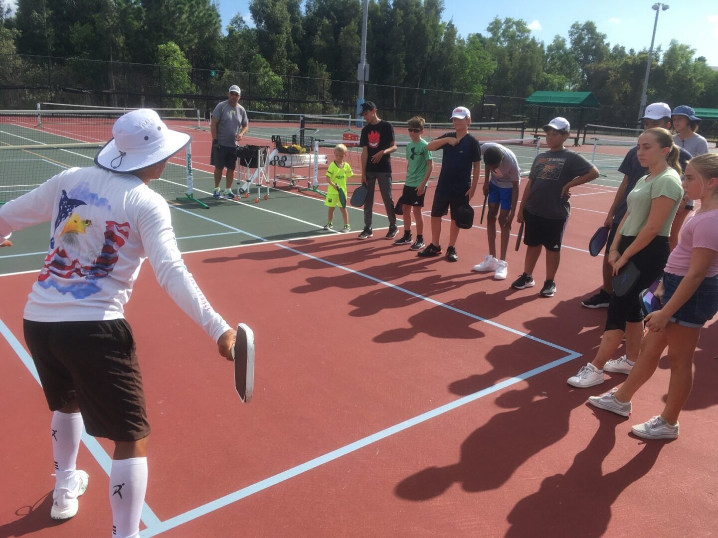 A group of people standing on top of a tennis court.