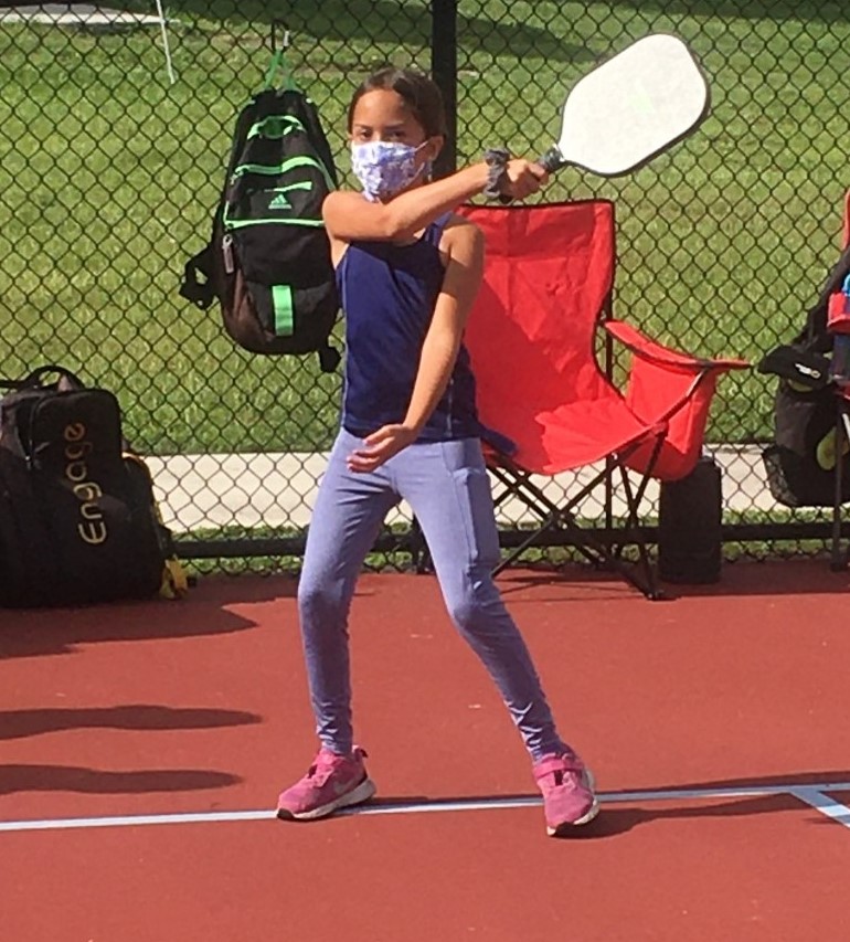 A girl in blue shirt holding a racket.