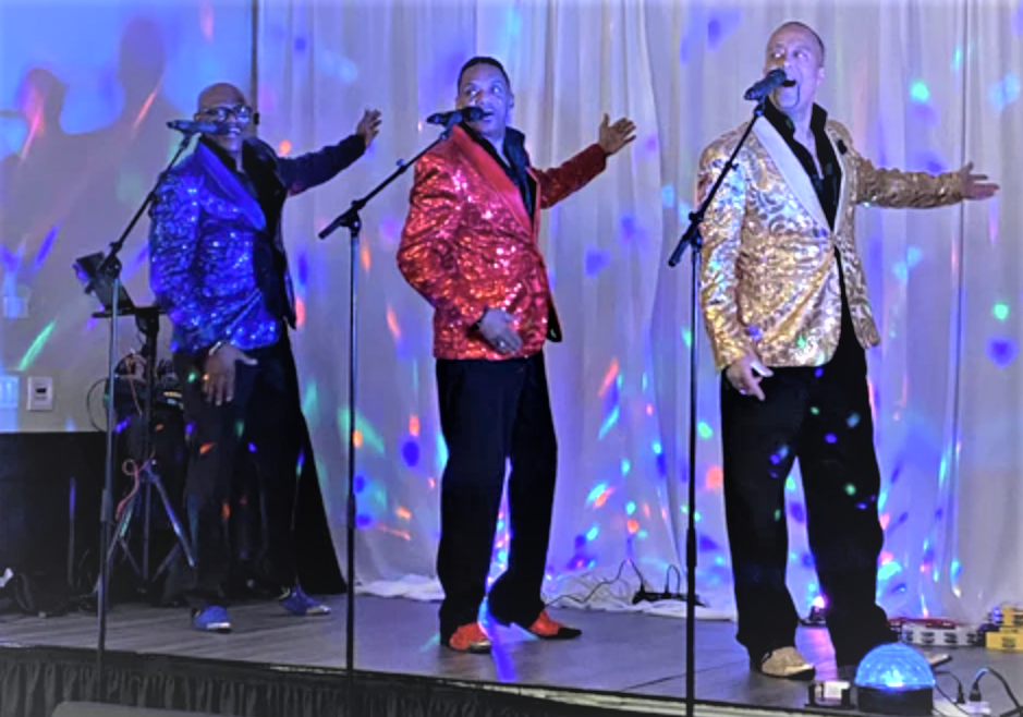 A group of men in colorful jackets singing on stage.