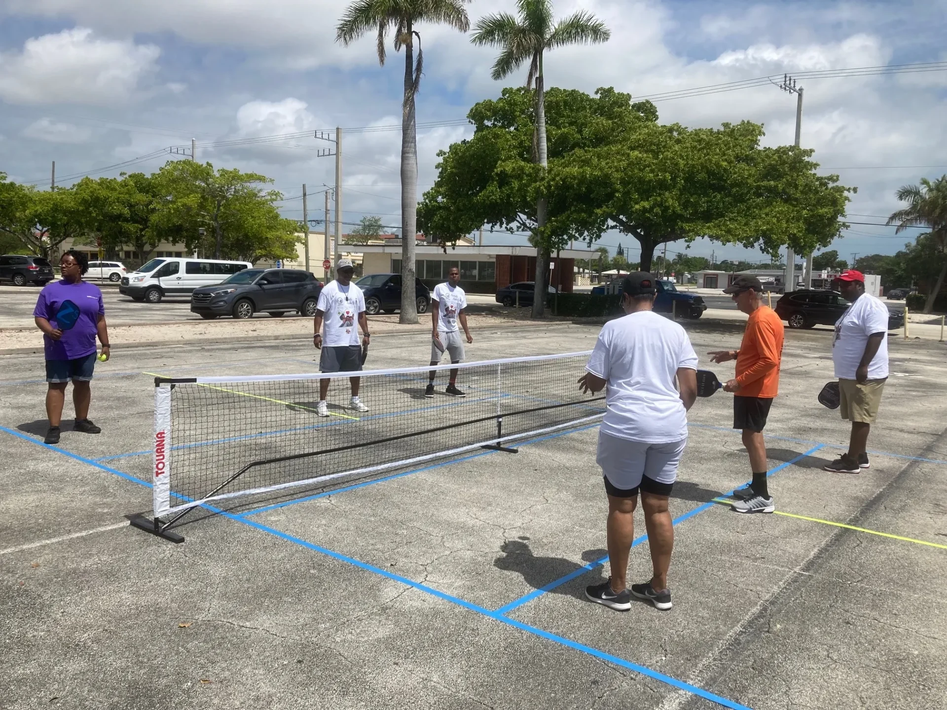 A group of people playing ping pong in the parking lot.