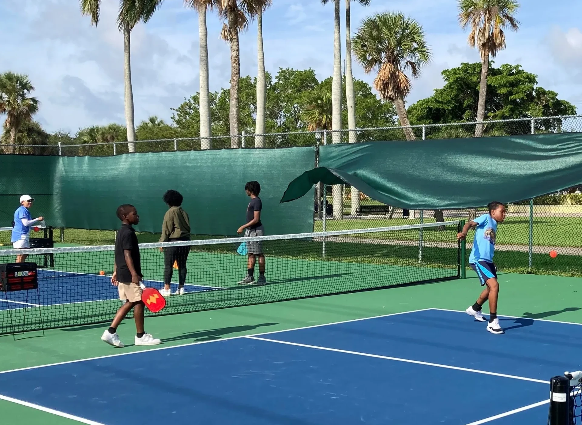 A group of young people playing tennis on a court.