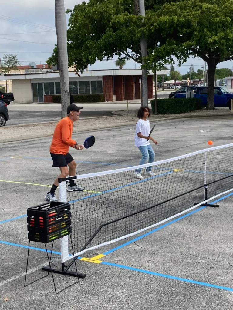 Two people playing tennis in a parking lot.