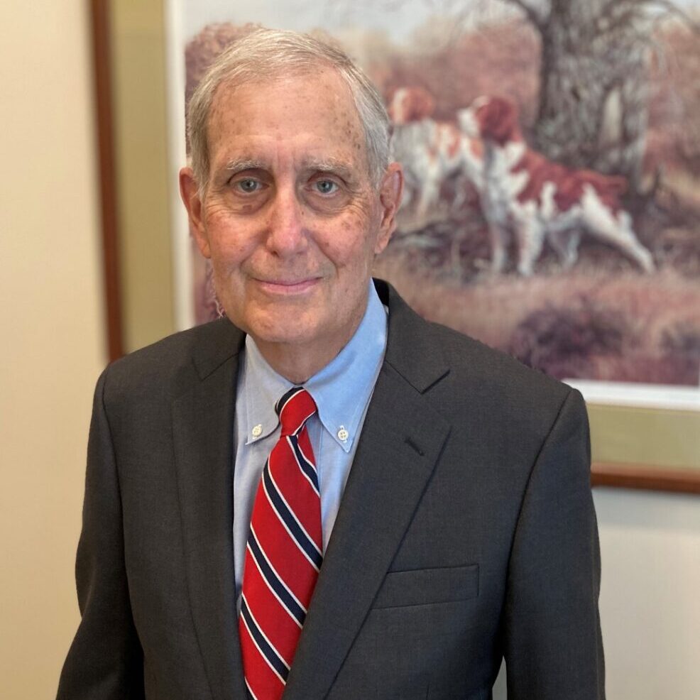 A man in a suit and tie standing next to a painting.